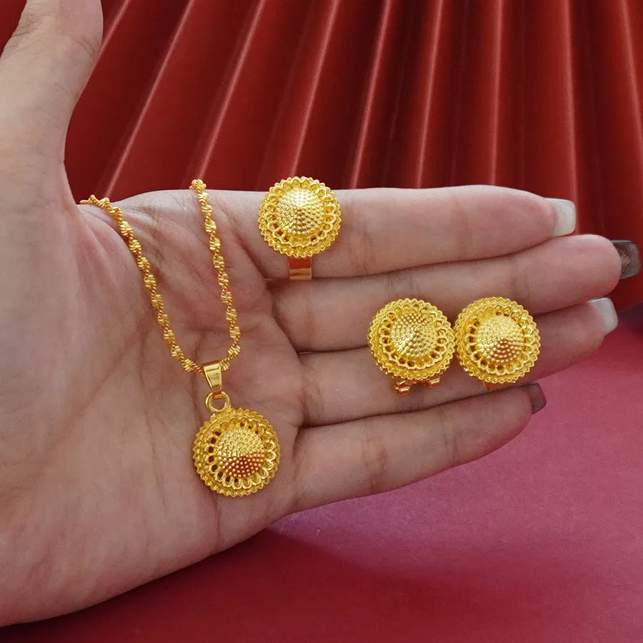Women's three-piece jewellery set showing gold electroplated necklace with floral pendant, matching earrings, and ring with Middle Eastern design