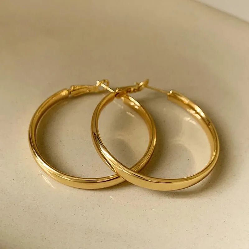 A pair of 40mm diameter metal circle earrings with a gold or silver electroplated finish.