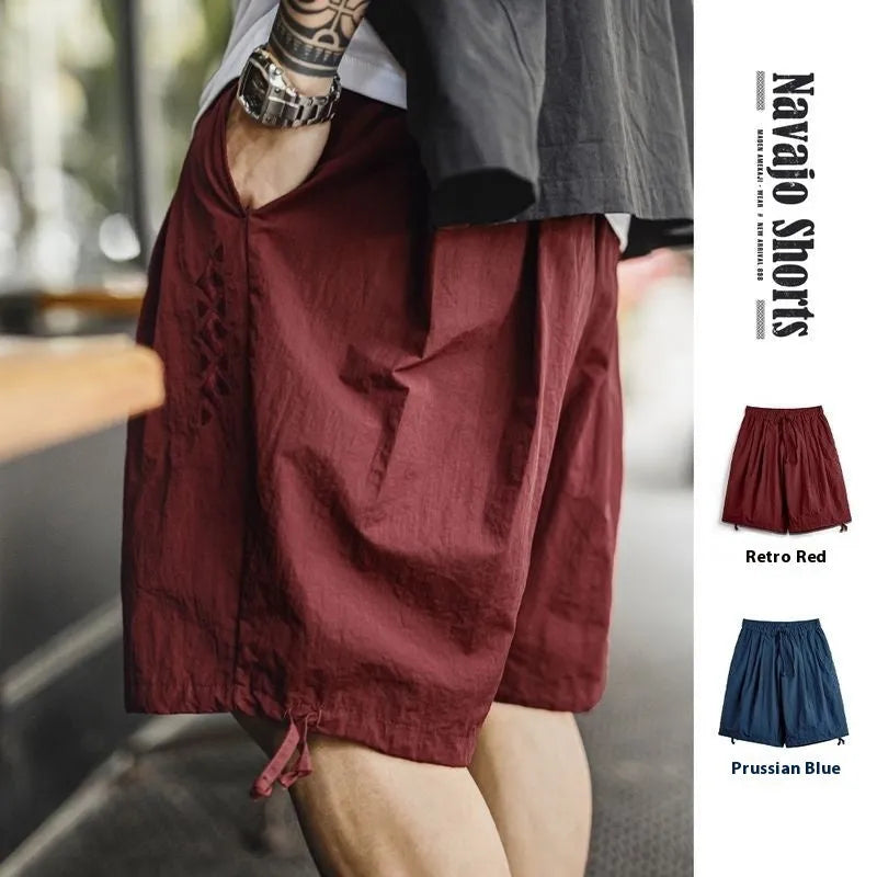 Men's loose fit Prussian blue nylon beach shorts with embroidery on a white background.