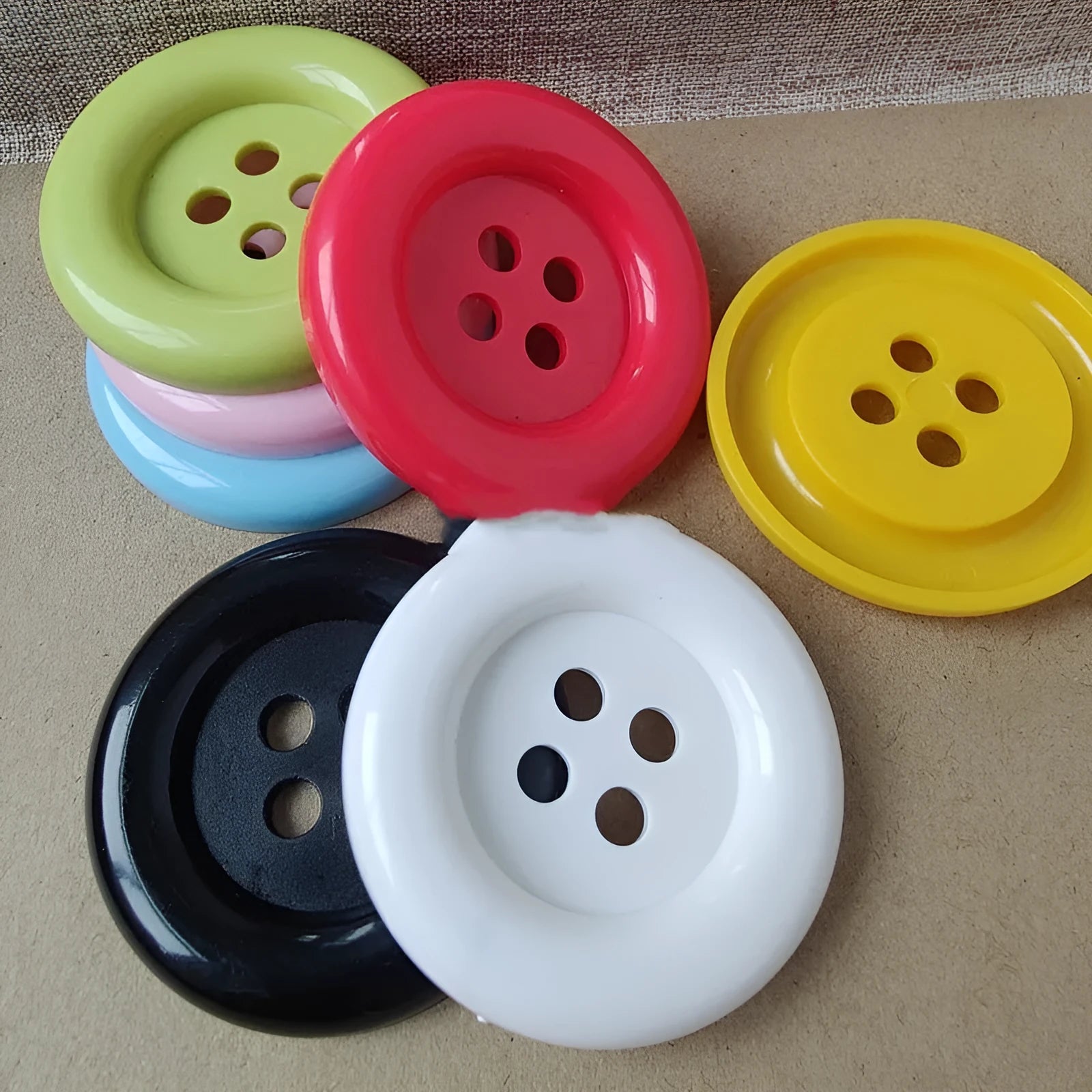 Assortment of oversized round plastic buttons in various colours with four holes.