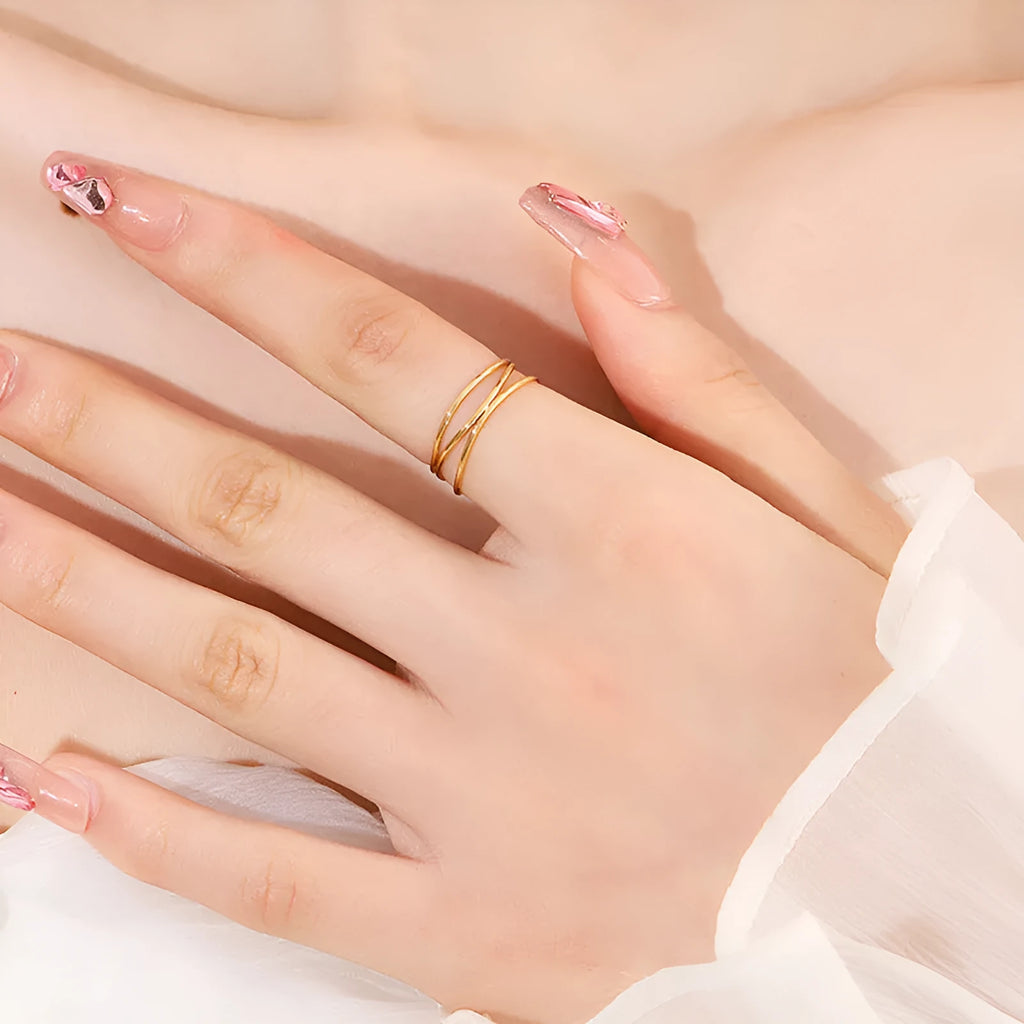 Gold-coloured titanium steel ring with a geometric three-layer coiled design on a hand.