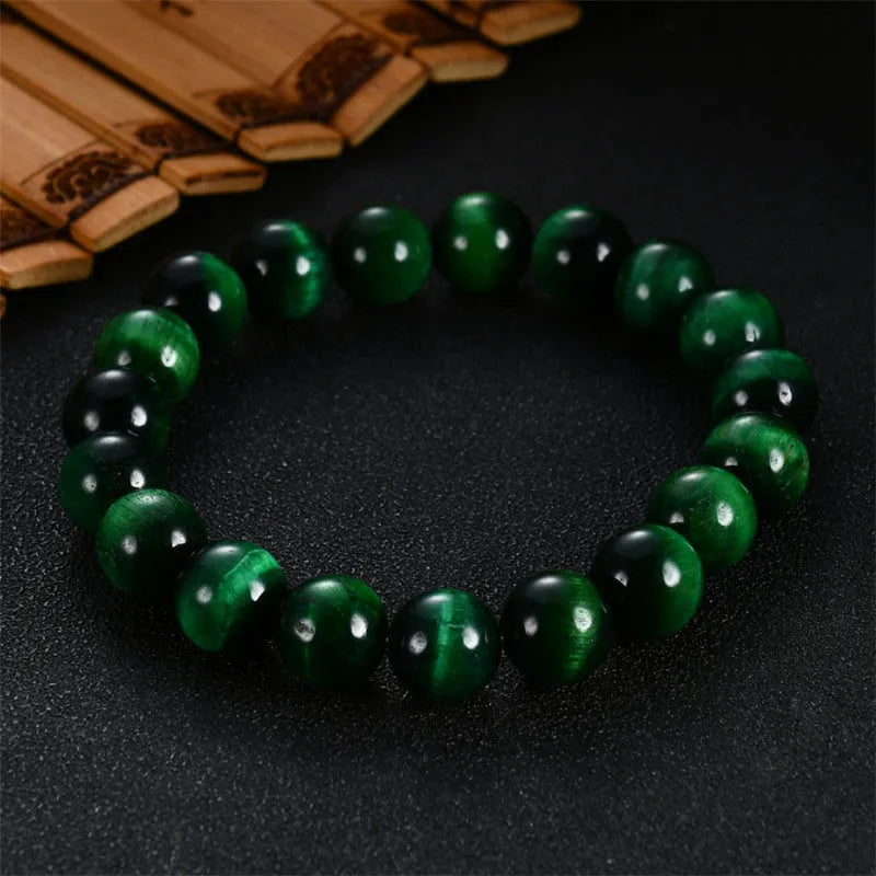 Green tiger eye stone bracelet with polished geometry beads and a sliding knot closure on a wrist.