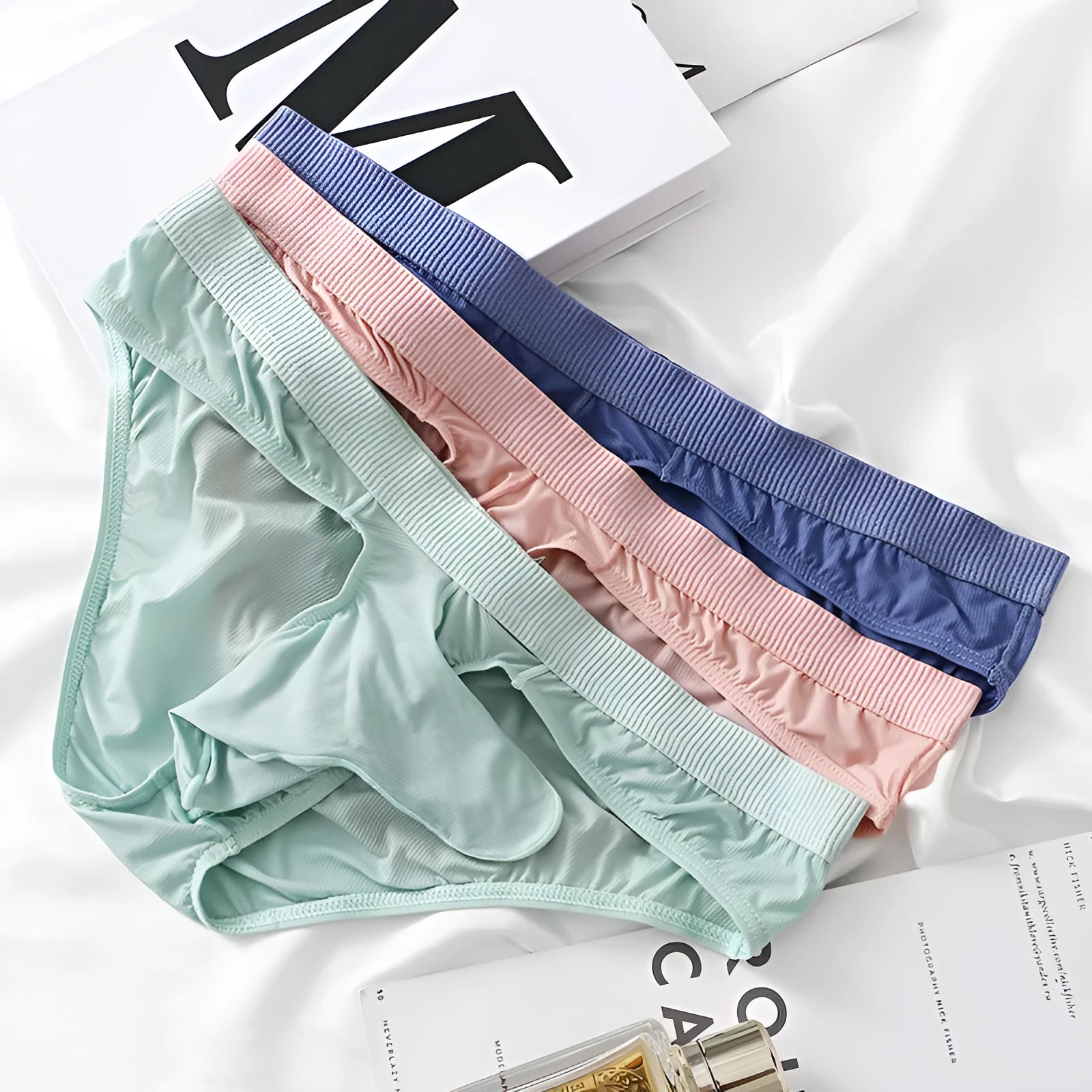 Men's low waist briefs underwear in Ice Silk fabric on a colour swatch showing black, grey, purple blue, light green, and pink.