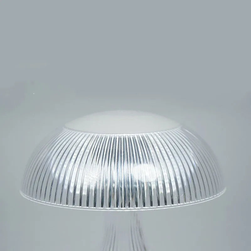 Small white rechargeable touch night lamp with acrylic body and plastic base on a wooden table.