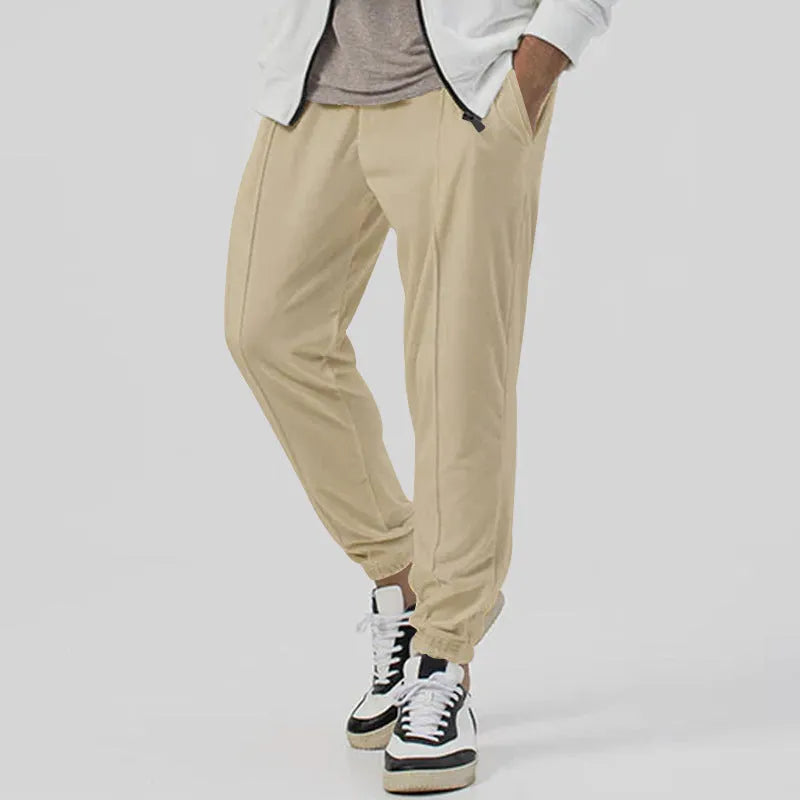 Man wearing gray straight-leg casual track sweatpants with a tapered fit and elastic waistband.