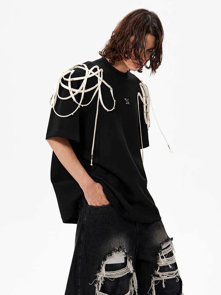 Black loose-fit short-sleeve t-shirt with padded shoulders featuring a decorative rivet and ribbon detail.
