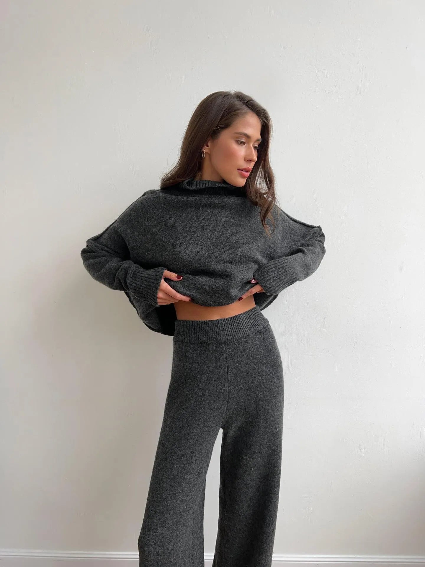Women's knitted acrylic suit set with side-slit top and matching trousers in a solid colour.