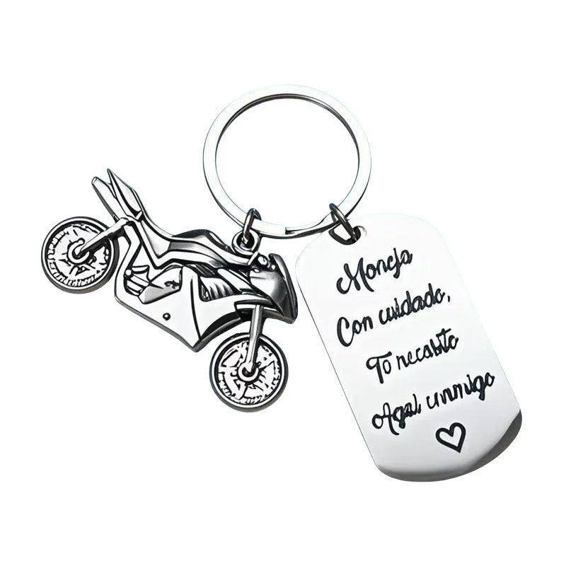 Stainless steel key ring with etched motorcycle design next to a grey flannel drawstring bag.