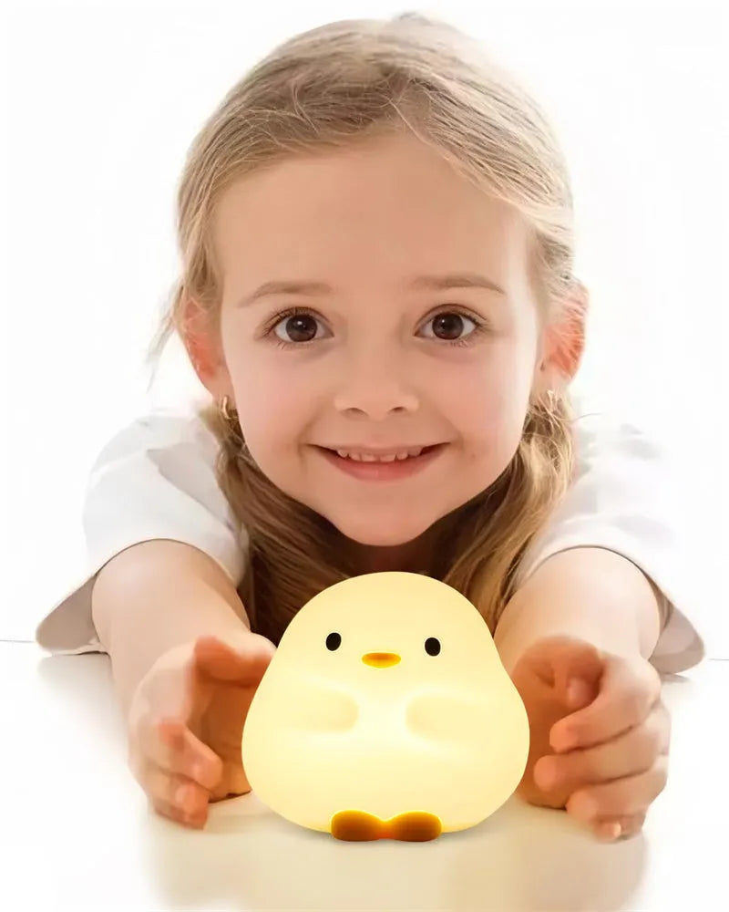 Cute duck-shaped silicone LED night lamp on a bedside table with warm light