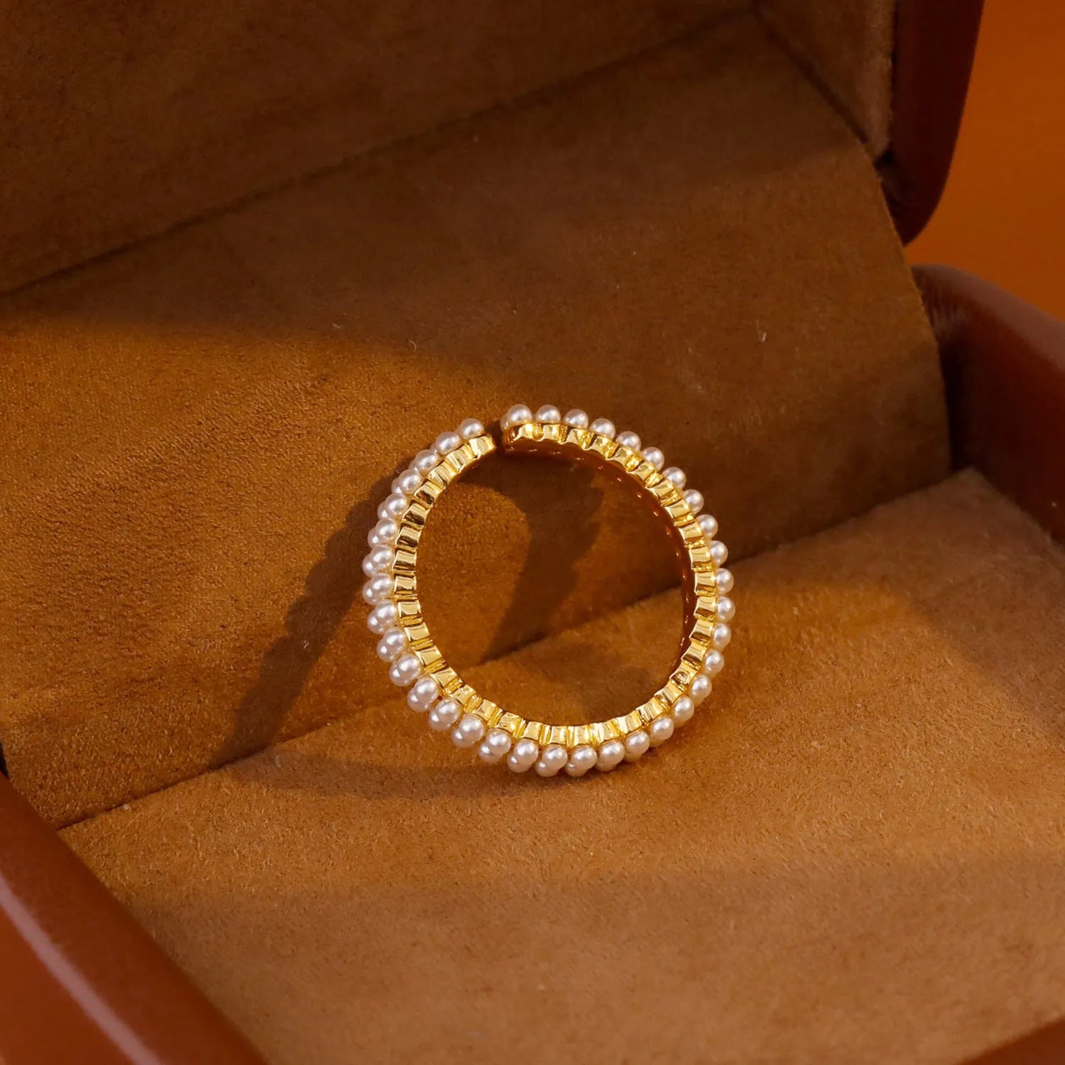 Gold electroplated open mouth geometry pearl ring for women on a neutral background.
