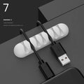 Smart cable holder with TPR flexible clips in black holding USB earphone and network cables on a desk
