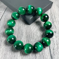 Green tiger eye stone bracelet with polished geometry beads and a sliding knot closure on a wrist.