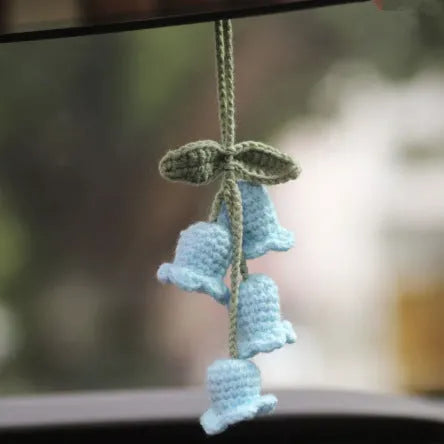 Green and white knitted wool car plant decoration with macramé texture and a white hanging rope.