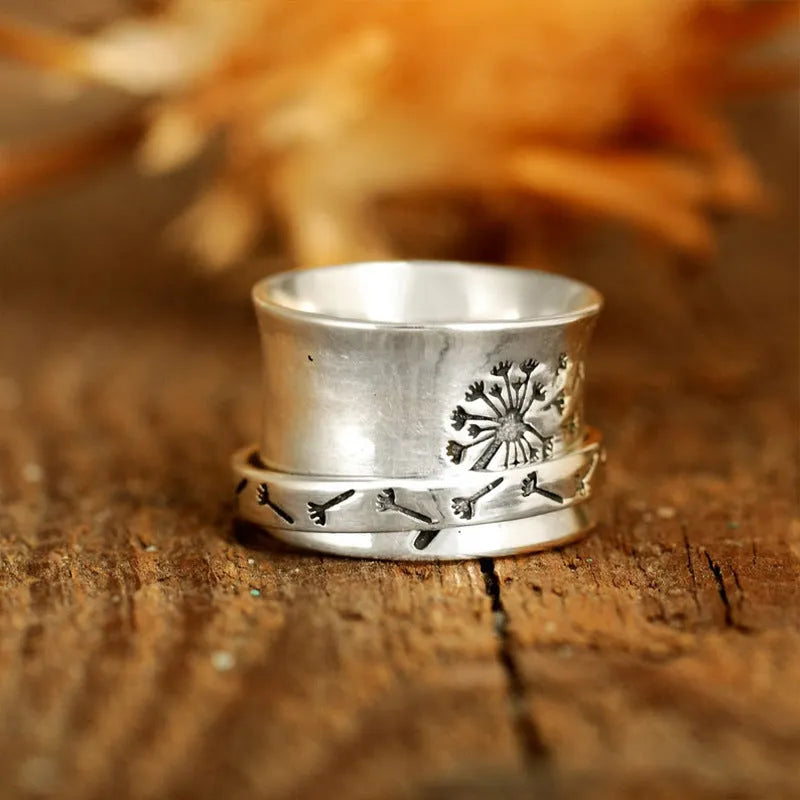Silver-coloured rotatable flower ring on a finger, showing the floral detail.
