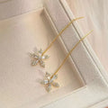 Long gold drop earrings for women with metal construction and secure fastening on white background