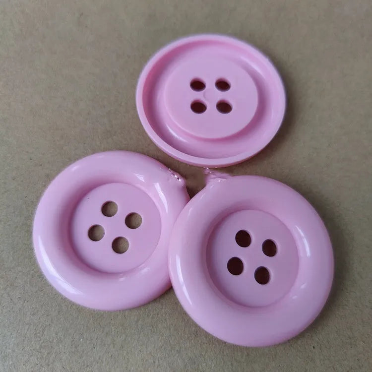 Assortment of oversized round plastic buttons in various colours with four holes.