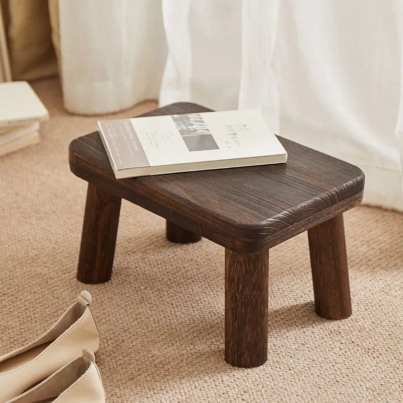 Solid wood shoe changing stool with a distressed rustic finish and sturdy bracket legs.