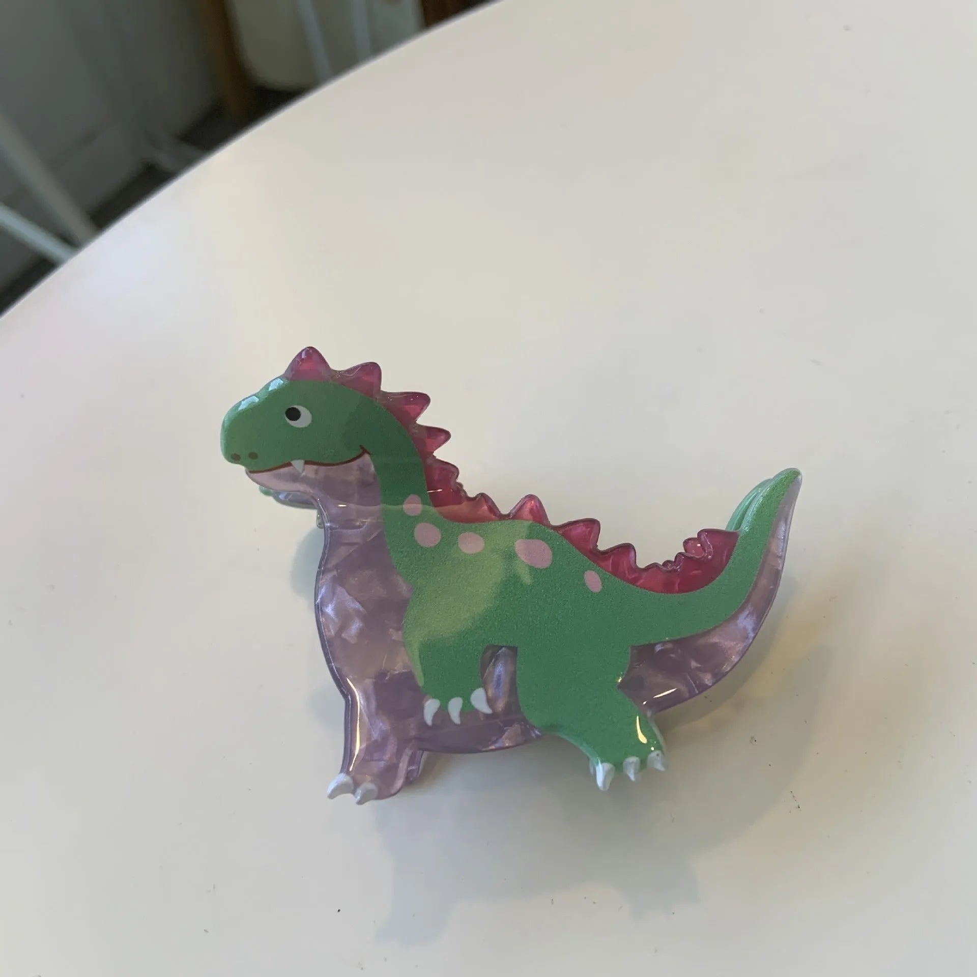 Acrylic hair clip with dinosaur design in various colours including blue, brown, green, pink and purple variants