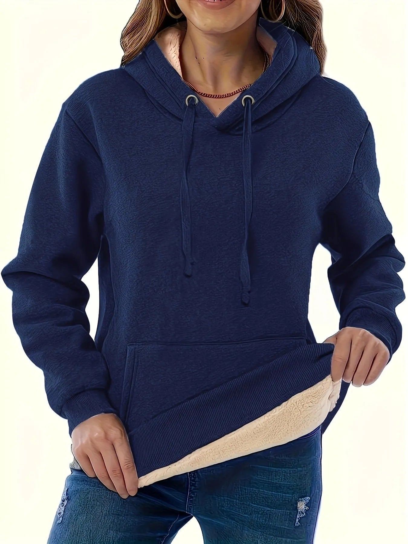 A woman wearing a thick, grey, loose-fit hooded sweatshirt with a 3D pattern and front pockets.