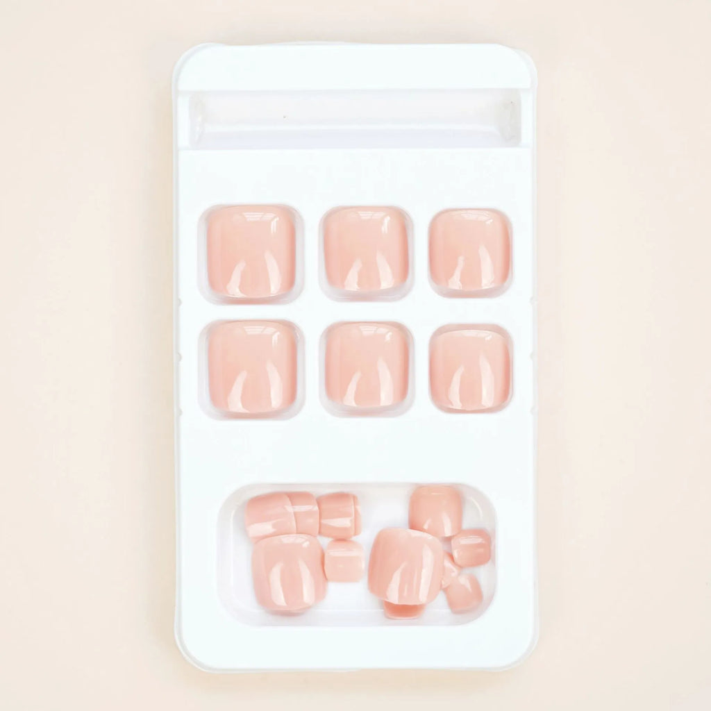 Set of plastic skin-coloured glue-on toe nail stickers with adhesive.