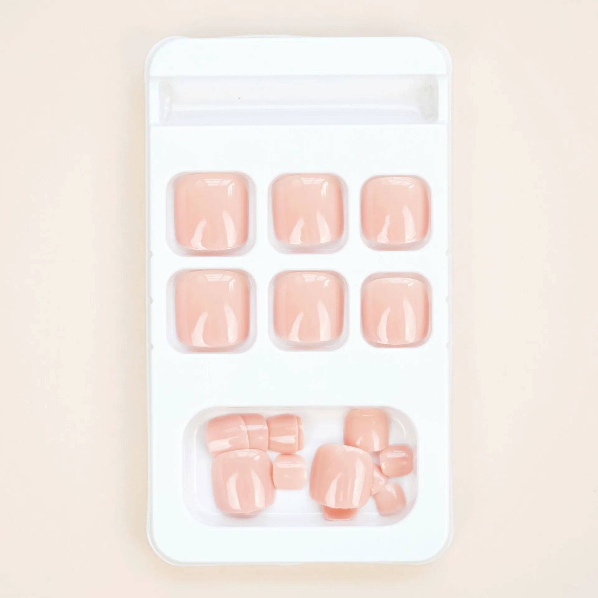 Set of plastic skin-coloured glue-on toe nail stickers with adhesive.