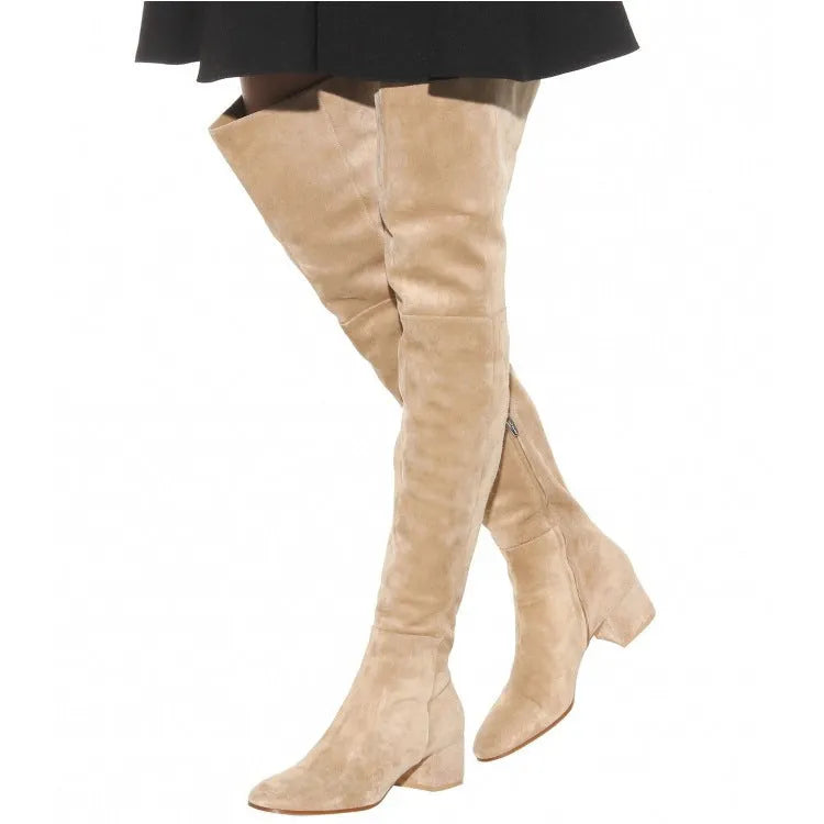 Women's grey suede over the knee flat boots with a low thick heel and pointed toe on a neutral background.