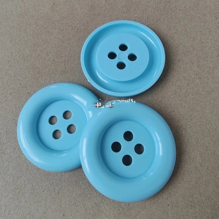 Assortment of oversized round plastic buttons in various colours with four holes.