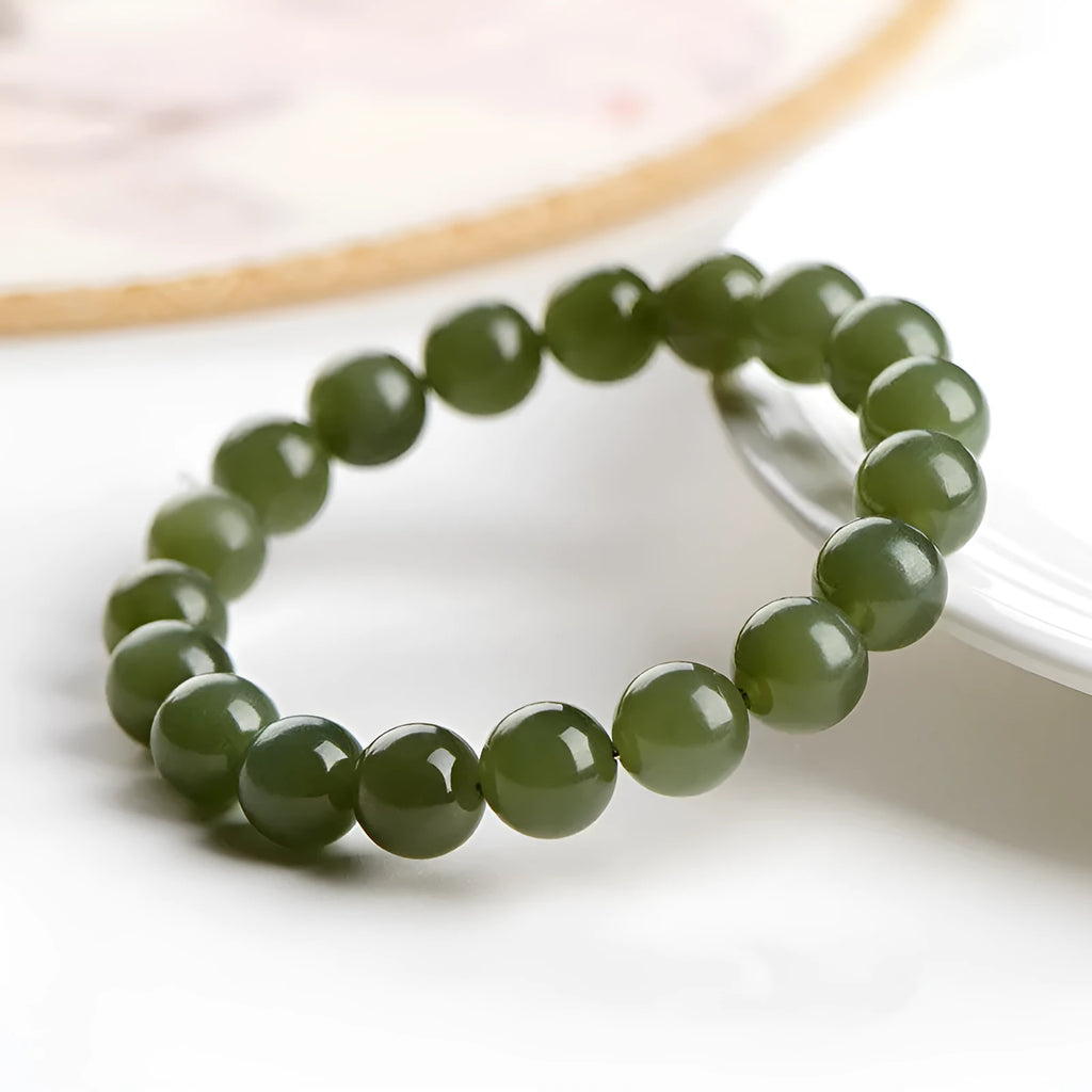 A polished Hetian Jade ball bracelet in a clear water colour on a wrist, showing spherical beads.