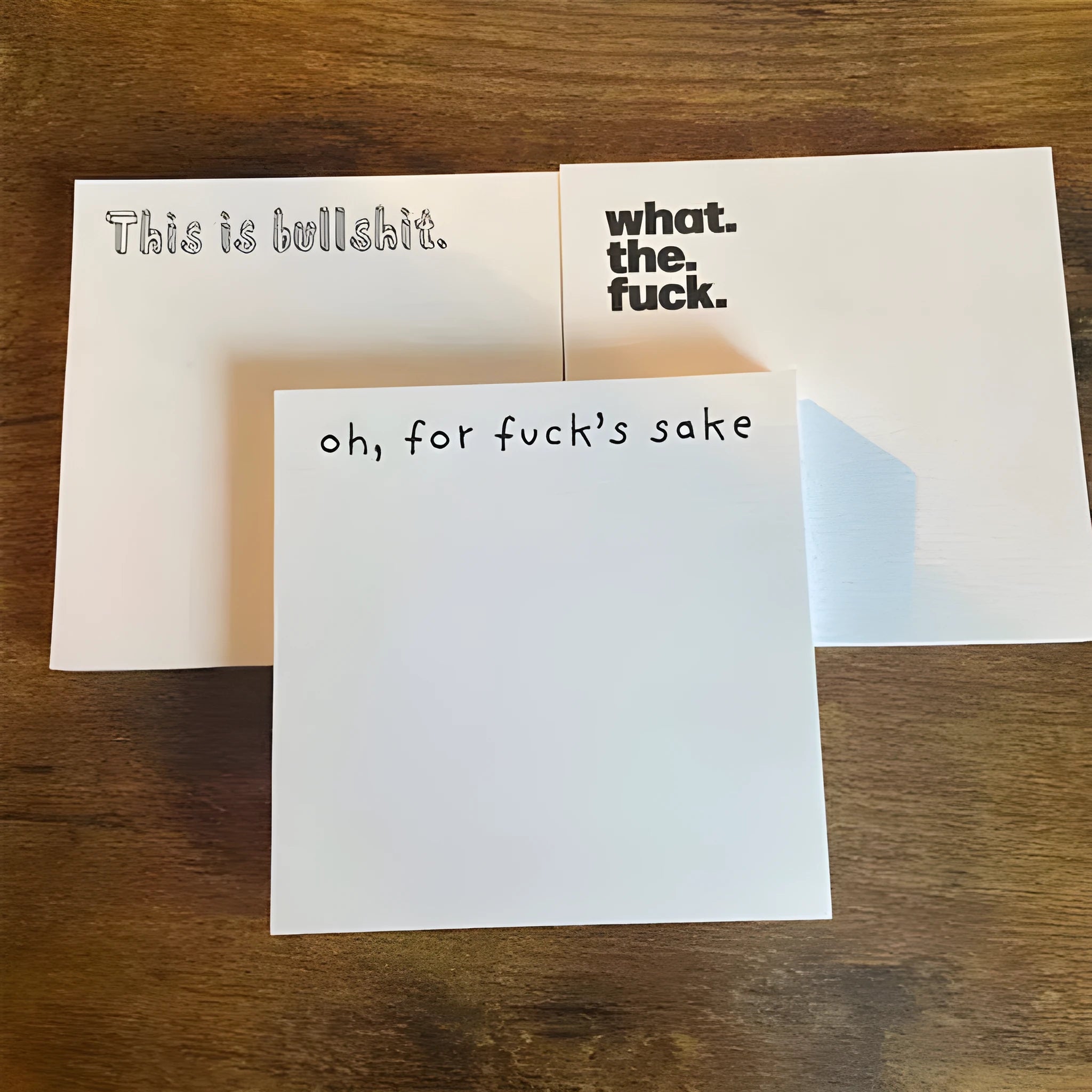 75mm square paper sticky note pad with funny English text cover designs on a desk.