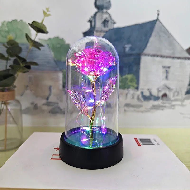 Small decorative night lamp with glass cover, plastic flower, and black base on a pink box.
