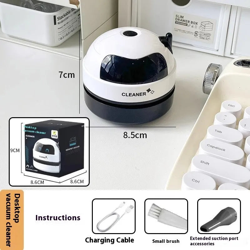 Handheld desktop vacuum cleaner in blue rocket design with USB charging cable on a wooden desk.
