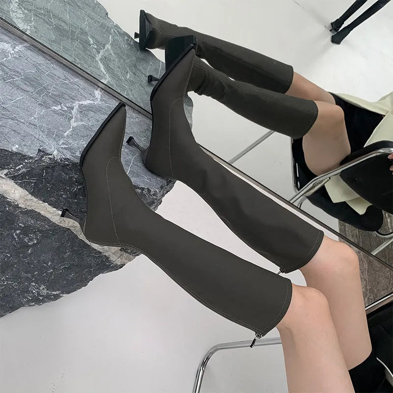 Black women's knee-high pointed toe boots with a stiletto heel and back zip fastening.