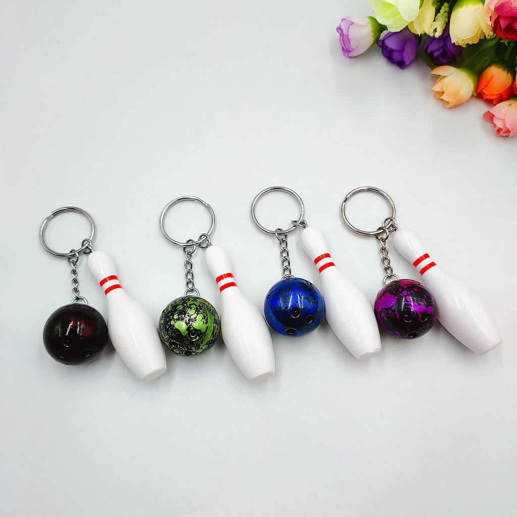 Miniature dark red bowling ball keychain on a metal key ring against a white background.
