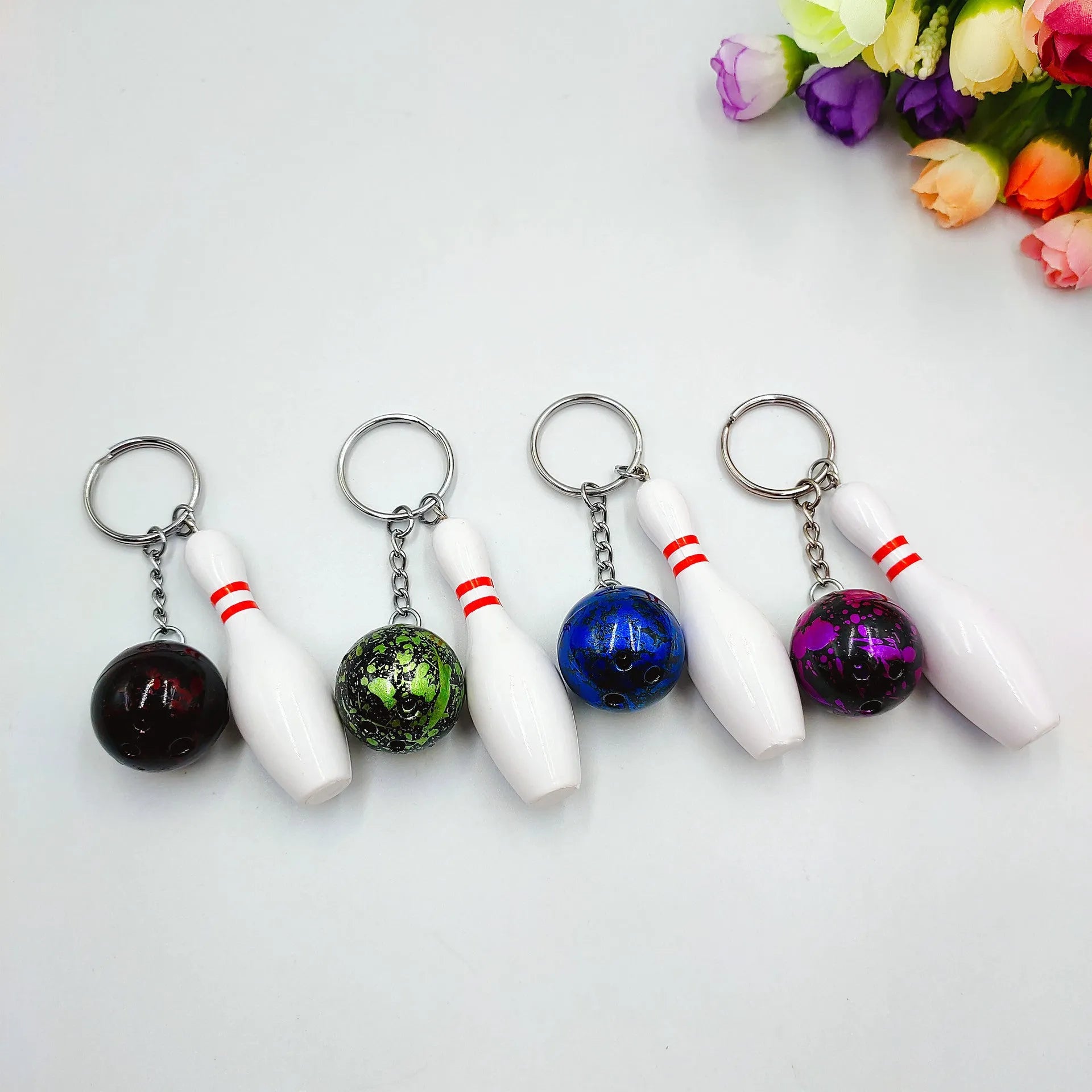 Miniature dark red bowling ball keychain on a metal key ring against a white background.