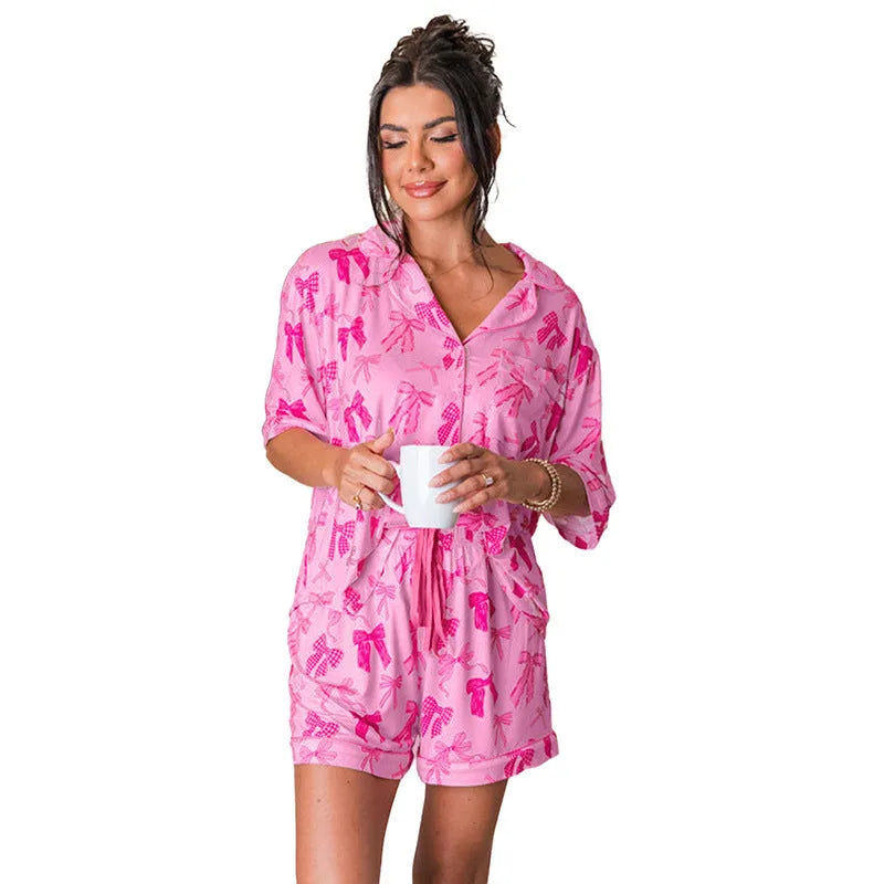Pink bow print two-piece polyester pajama set shown as matching top and trousers