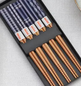 Set of five pairs of bamboo chopsticks with Japanese lucky cat and elegant blue patterns on a table.