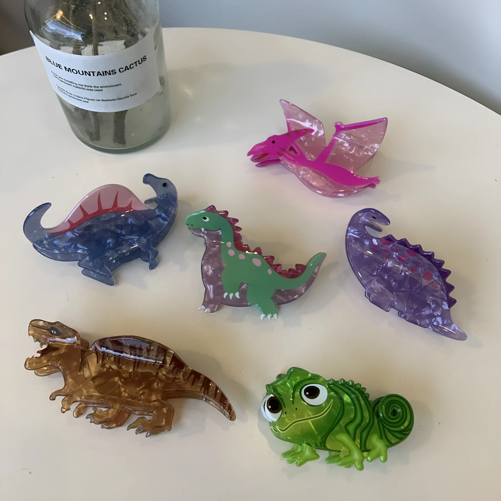 Acrylic hair clip with dinosaur design in various colours including blue, brown, green, pink and purple variants