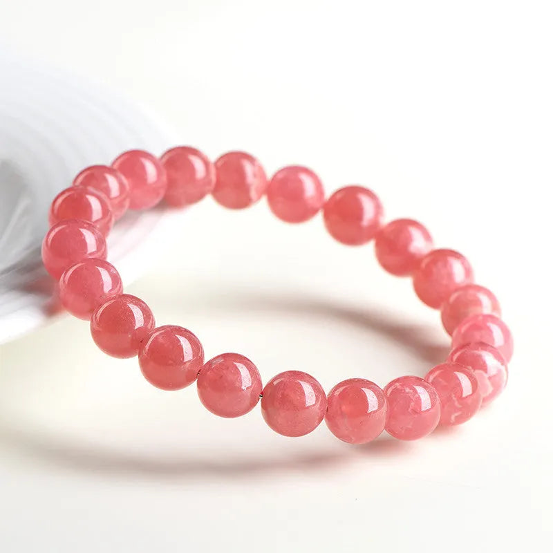 Women's geometric crystal bracelet with red rhodochrosite stone and a Longevity Lock charm on a wrist.