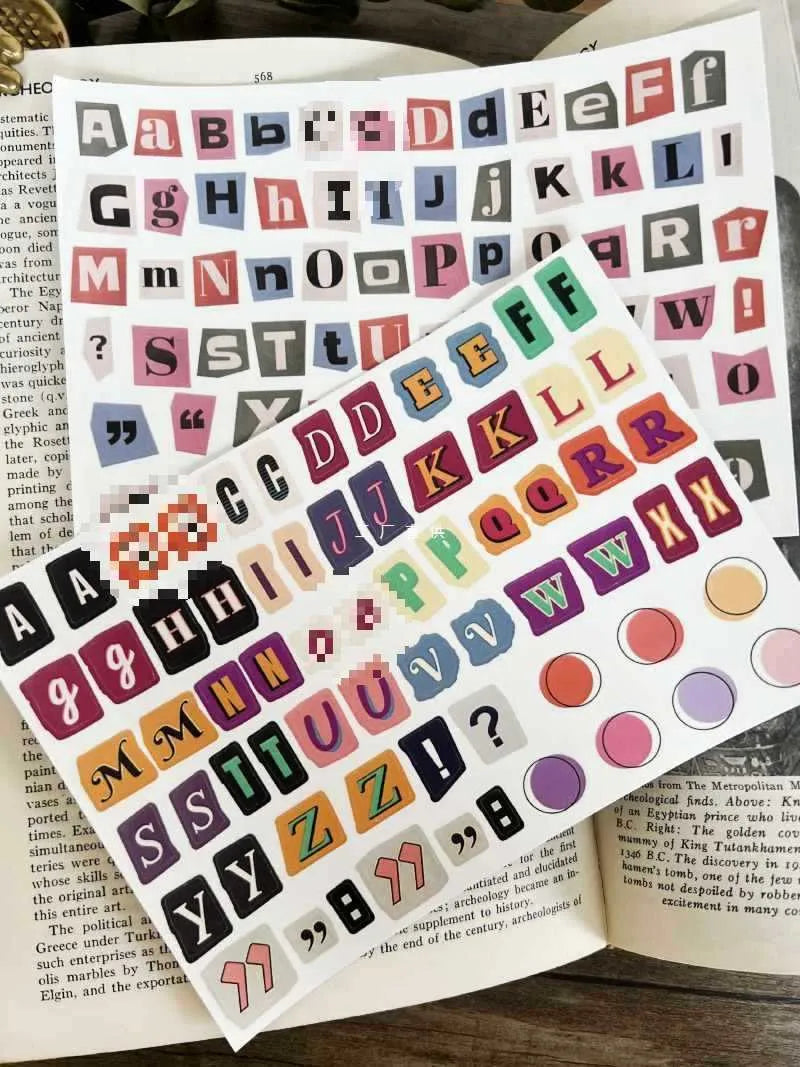 Set of printed cute-style stickers showing English letters A, B, C, D, E, numbers, symbols, and weekly words on a sheet.