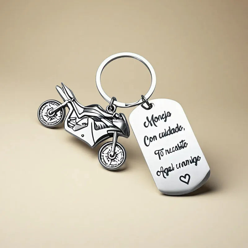Stainless steel key ring with etched motorcycle design next to a grey flannel drawstring bag.