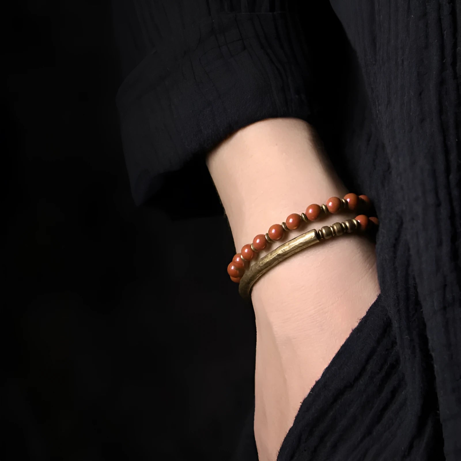 Layered retro ethnic bracelet with natural stone beads and antique brass details on a wrist.