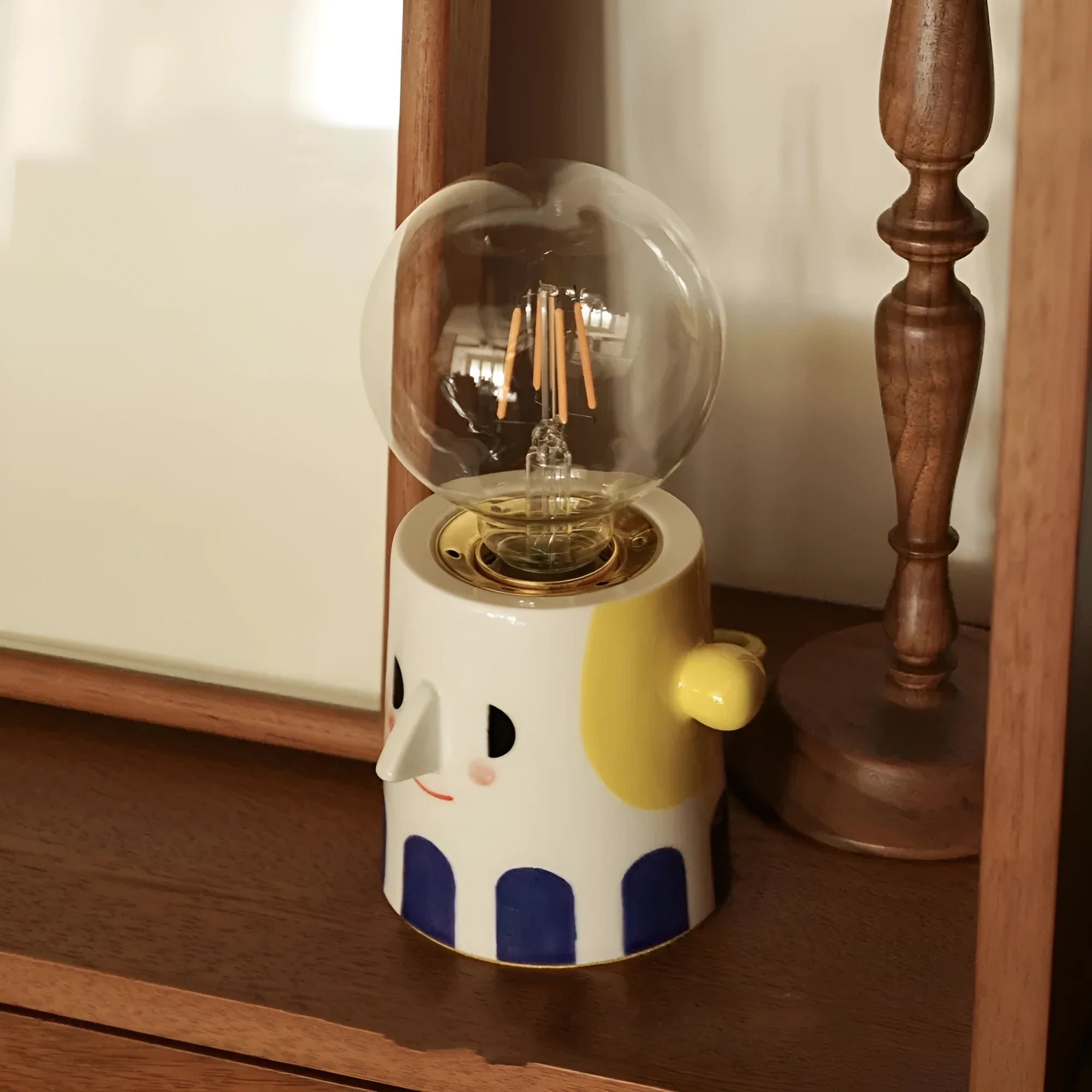 Handmade ceramic table lamp with ball headlight design on a bedside table