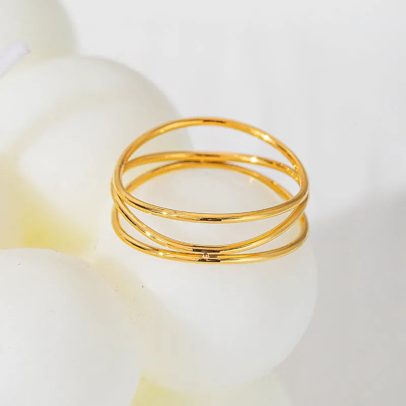 Gold-coloured titanium steel ring with a geometric three-layer coiled design on a hand.