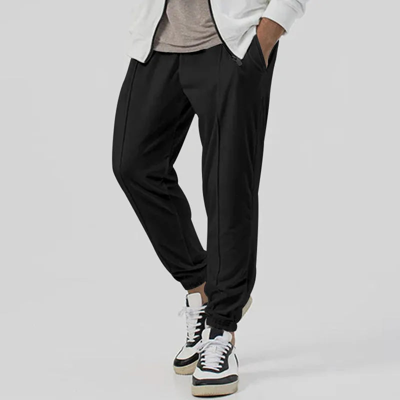 Man wearing gray straight-leg casual track sweatpants with a tapered fit and elastic waistband.