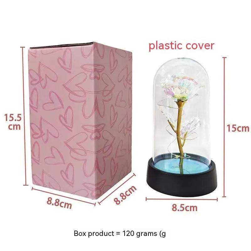 Small decorative night lamp with glass cover, plastic flower, and black base on a pink box.