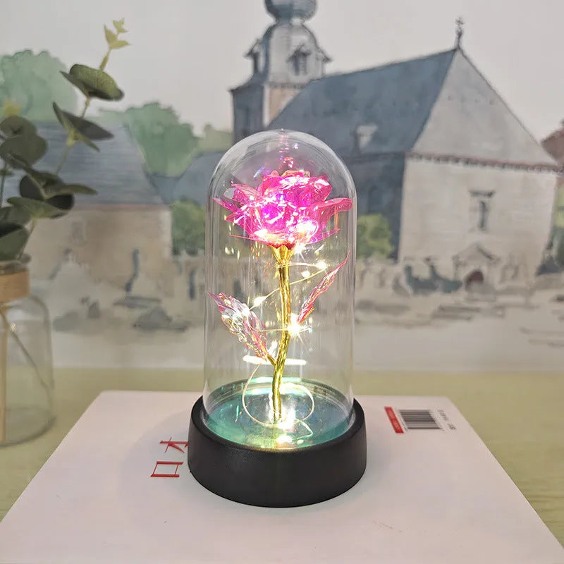 Small decorative night lamp with glass cover, plastic flower, and black base on a pink box.