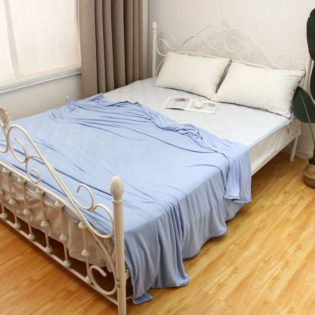 A blue polyester cooling blanket with Q-Max 0.4 technology laid on a bed.