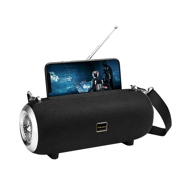 Square fabric portable Bluetooth speaker with FM antenna, shoulder strap, and phone stand groove.