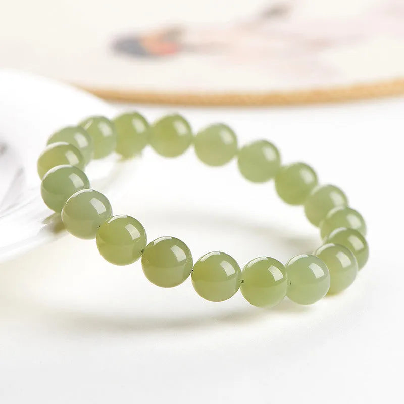 A polished Hetian Jade ball bracelet in a clear water colour on a wrist, showing spherical beads.