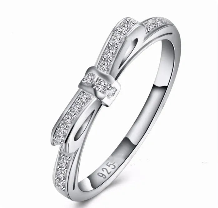 Silver electroplated ring with a detailed bow shape and set zircon crystal accents.